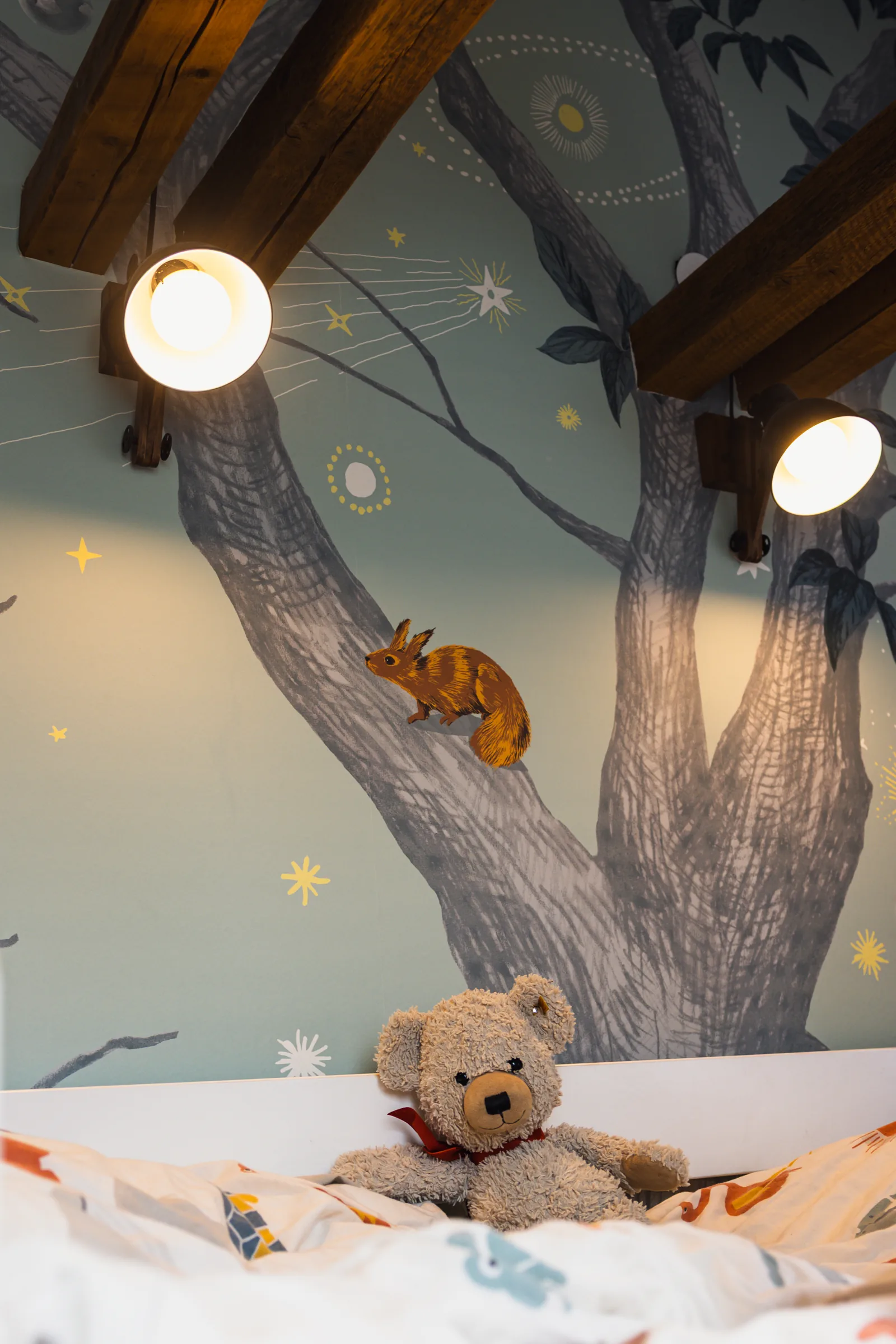 Detail des gemalten Waldmotivs: ein Eichhörnchen am Baumstamm, darüber zwei Leuchten am Hochbett